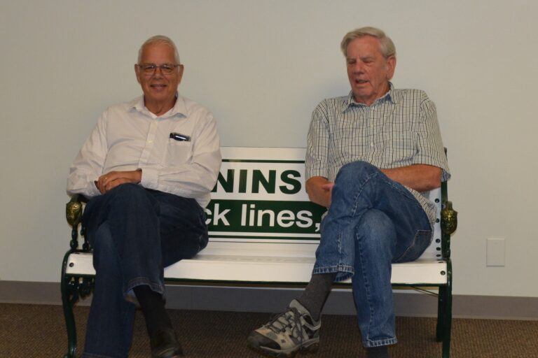Stan Vander Pol and Merv Haveman on a bench made from a trailer door celebrating 70 years in business